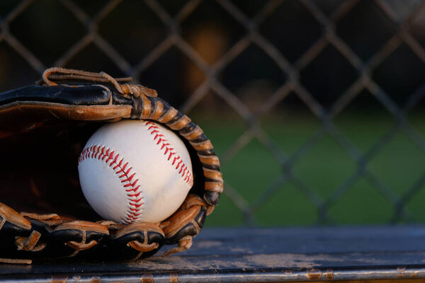 Baseball background with ball and glove close up on dugout bench.