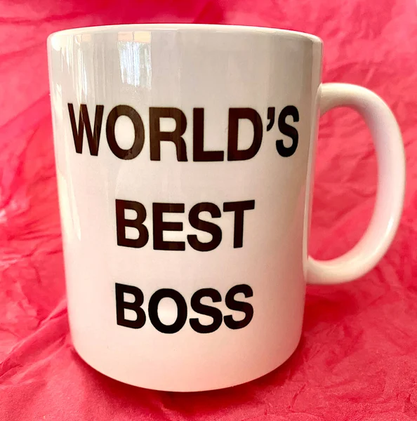 世界上最好的老板 在一个粉色背景的白色杯子上 图库照片