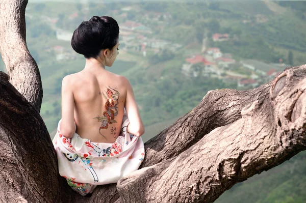 Mujer con tatuaje de serpiente en la espalda en la rama del árbol (original ) — Foto de Stock