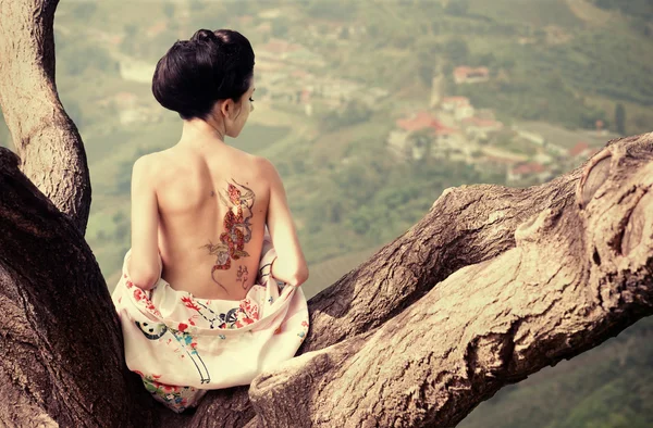 Femme avec tatouage de serpent sur le dos sur la branche de l'arbre — Photo