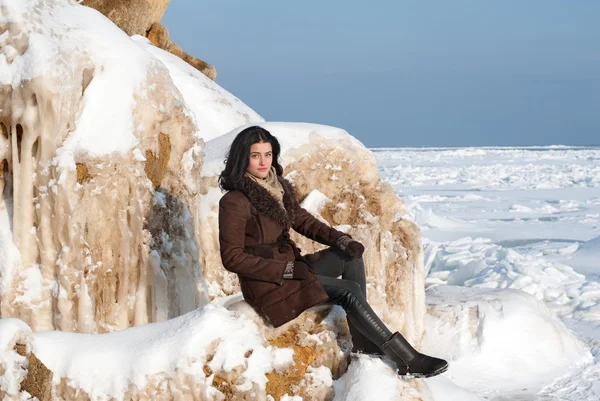 Брюнетка сидит на покрытой льдом скале — стоковое фото