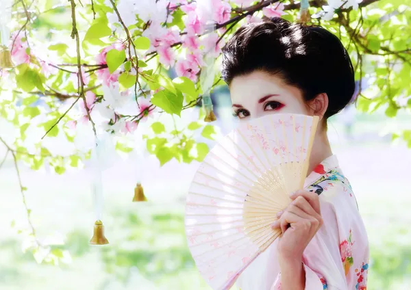 Geisha with fan in the garden Stock Photo