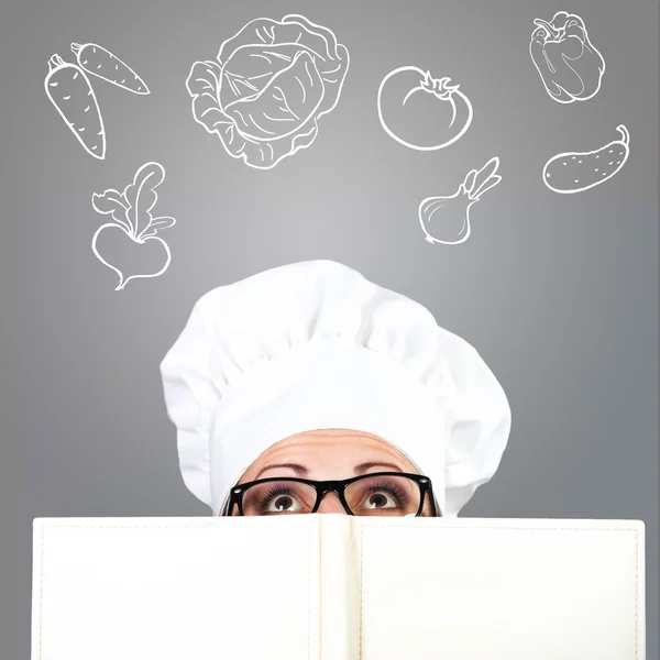 Chef mujer mirando sobre el libro de cocina de verduras —  Fotos de Stock