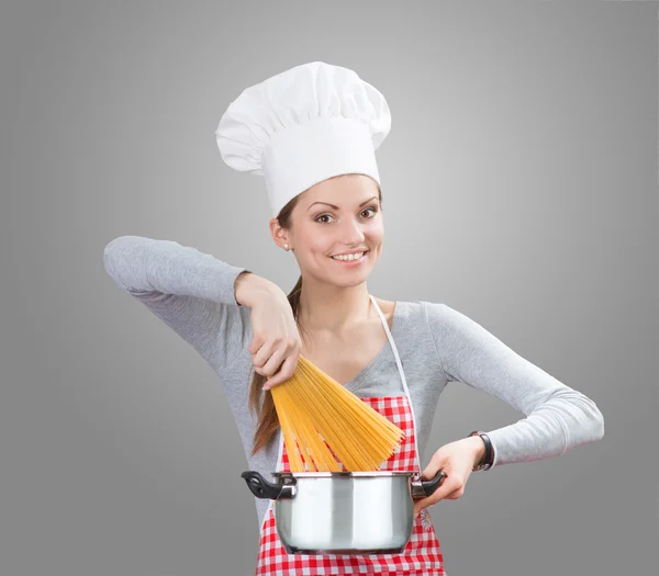 Mujer sonriente agregando la pasta a la olla — Foto de Stock