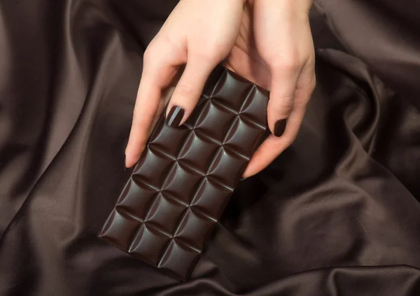 Vrouwelijke handen met de donkere chocolade bar — Stockfoto