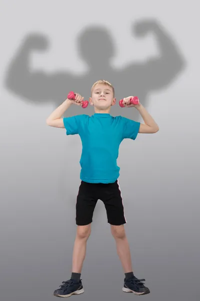 Funny slim boy with bodybuilder's silhouette behind him — Stock Photo, Image