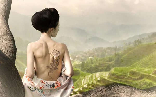 Woman with snake tattoo on her back on the tree branch — Stock Photo, Image