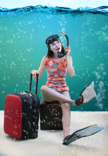 Забавная девушка со своим багажом, сидящая под морем — стоковое фото