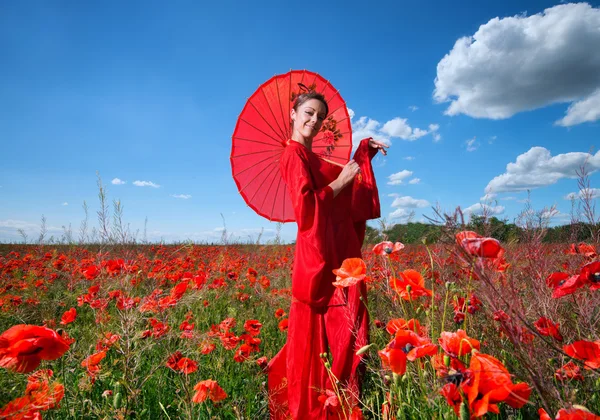 Frau im roten Kimono posiert im Mohnfeld — Stockfoto