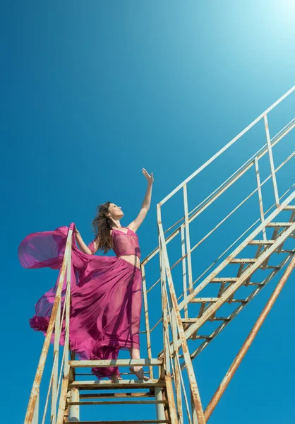 Chica en vestido carmesí en la vieja construcción metálica — Foto de Stock