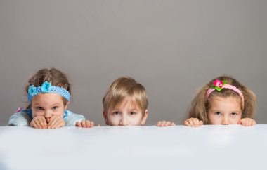 Çocuklar masanın arkasından kamera bakıyor
