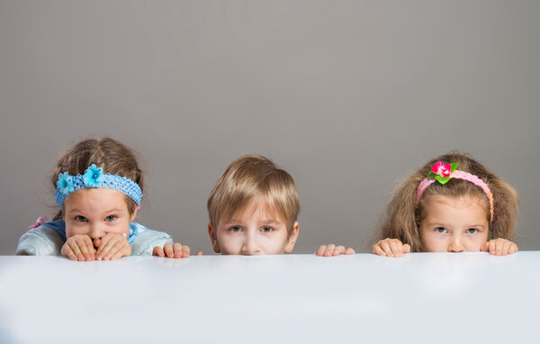 Children looking at camera from behind the table