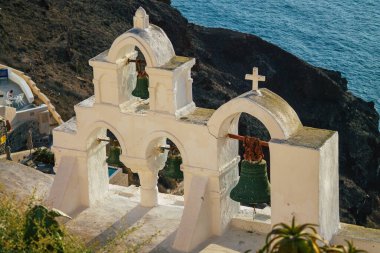 Santorini Adası, Oia, Yunanistan - 21 Ekim 2021 Okyanus kıyısındaki geleneksel ortodoks kilisesi, bu adanın tipik bir örneği, antik aktif volkanın yan tarafında yer almaktadır.