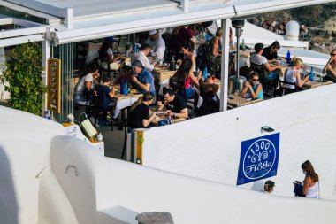 Santorini, Oia, Yunanistan - 24 Ekim 2021 Coronavirus salgını sırasında Yunanistan 'ı vuran ve sokakta maske takan ünlü tünemiş Oia kasabasını ziyaret eden turist topluluğu zorunlu değil