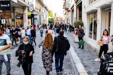 Atina, Yunanistan - Yunanistan - 07 Kasım 2021 Coronavirüs salgını sırasında Ermou Caddesi 'nde yürüyen ve alışveriş yapan kalabalık, maskeyi sokakta takmak zorunda değil, fakat pek çok kişi takıyor.