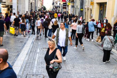 Atina, Yunanistan - Yunanistan - 07 Kasım 2021 Coronavirüs salgını sırasında Ermou Caddesi 'nde yürüyen ve alışveriş yapan kalabalık, maskeyi sokakta takmak zorunda değil, fakat pek çok kişi takıyor.