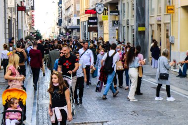 Atina, Yunanistan - Yunanistan - 07 Kasım 2021 Coronavirüs salgını sırasında Ermou Caddesi 'nde yürüyen ve alışveriş yapan kalabalık, maskeyi sokakta takmak zorunda değil, fakat pek çok kişi takıyor.