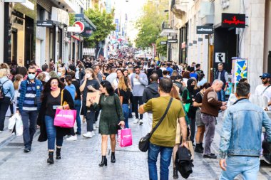 Atina, Yunanistan - Yunanistan - 07 Kasım 2021 Coronavirüs salgını sırasında Ermou Caddesi 'nde yürüyen ve alışveriş yapan kalabalık, maskeyi sokakta takmak zorunda değil, fakat pek çok kişi takıyor.