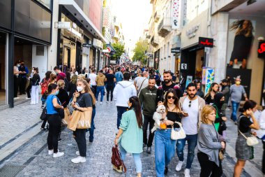 Atina, Yunanistan - Yunanistan - 07 Kasım 2021 Coronavirüs salgını sırasında Ermou Caddesi 'nde yürüyen ve alışveriş yapan kalabalık, maskeyi sokakta takmak zorunda değil, fakat pek çok kişi takıyor.
