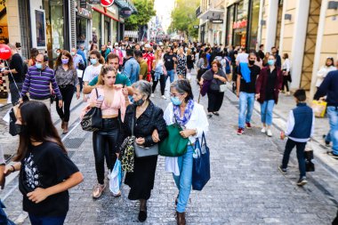 Atina, Yunanistan - Yunanistan - 07 Kasım 2021 Coronavirüs salgını sırasında Ermou Caddesi 'nde yürüyen ve alışveriş yapan kalabalık, maskeyi sokakta takmak zorunda değil, fakat pek çok kişi takıyor.