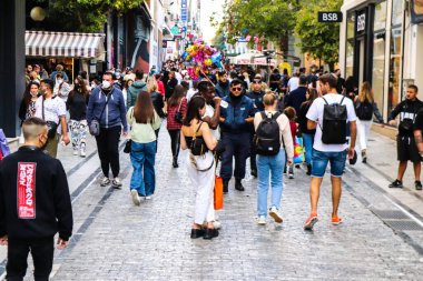 Atina, Yunanistan - Yunanistan - 07 Kasım 2021 Coronavirüs salgını sırasında Ermou Caddesi 'nde yürüyen ve alışveriş yapan kalabalık, maskeyi sokakta takmak zorunda değil, fakat pek çok kişi takıyor.