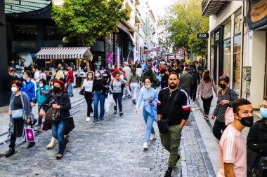Atina, Yunanistan - Yunanistan - 07 Kasım 2021 Coronavirüs salgını sırasında Ermou Caddesi 'nde yürüyen ve alışveriş yapan kalabalık, maskeyi sokakta takmak zorunda değil, fakat pek çok kişi takıyor.
