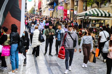 Atina, Yunanistan - Yunanistan - 07 Kasım 2021 Coronavirüs salgını sırasında Ermou Caddesi 'nde yürüyen ve alışveriş yapan kalabalık, maskeyi sokakta takmak zorunda değil, fakat pek çok kişi takıyor.