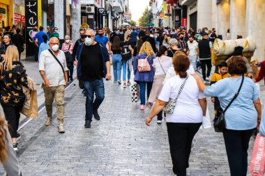 Atina, Yunanistan - Yunanistan - 07 Kasım 2021 Coronavirüs salgını sırasında Ermou Caddesi 'nde yürüyen ve alışveriş yapan kalabalık, maskeyi sokakta takmak zorunda değil, fakat pek çok kişi takıyor.