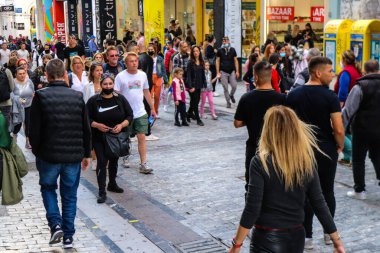 Atina, Yunanistan - Yunanistan - 07 Kasım 2021 Coronavirüs salgını sırasında Ermou Caddesi 'nde yürüyen ve alışveriş yapan kalabalık, maskeyi sokakta takmak zorunda değil, fakat pek çok kişi takıyor.