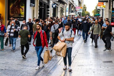 Atina, Yunanistan - Yunanistan - 07 Kasım 2021 Coronavirüs salgını sırasında Ermou Caddesi 'nde yürüyen ve alışveriş yapan kalabalık, maskeyi sokakta takmak zorunda değil, fakat pek çok kişi takıyor.