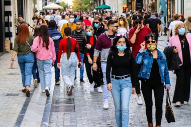 Atina, Yunanistan - Yunanistan - 07 Kasım 2021 Coronavirüs salgını sırasında Ermou Caddesi 'nde yürüyen ve alışveriş yapan kalabalık, maskeyi sokakta takmak zorunda değil, fakat pek çok kişi takıyor.