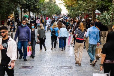 Atina, Yunanistan - Yunanistan - 07 Kasım 2021 Coronavirüs salgını sırasında Ermou Caddesi 'nde yürüyen ve alışveriş yapan kalabalık, maskeyi sokakta takmak zorunda değil, fakat pek çok kişi takıyor.