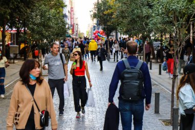 Atina, Yunanistan - Yunanistan - 07 Kasım 2021 Coronavirüs salgını sırasında Ermou Caddesi 'nde yürüyen ve alışveriş yapan kalabalık, maskeyi sokakta takmak zorunda değil, fakat pek çok kişi takıyor.
