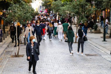 Atina, Yunanistan - Yunanistan - 07 Kasım 2021 Coronavirüs salgını sırasında Ermou Caddesi 'nde yürüyen ve alışveriş yapan kalabalık, maskeyi sokakta takmak zorunda değil, fakat pek çok kişi takıyor.