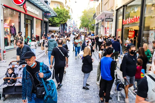 Atina, Yunanistan - Yunanistan - 07 Kasım 2021 Coronavirüs salgını sırasında Ermou Caddesi 'nde yürüyen ve alışveriş yapan kalabalık, maskeyi sokakta takmak zorunda değil, fakat pek çok kişi takıyor.