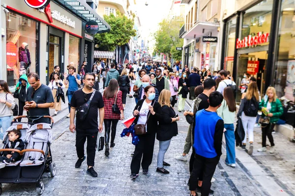 Atina, Yunanistan - Yunanistan - 07 Kasım 2021 Coronavirüs salgını sırasında Ermou Caddesi 'nde yürüyen ve alışveriş yapan kalabalık, maskeyi sokakta takmak zorunda değil, fakat pek çok kişi takıyor.