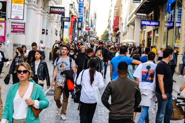Atina, Yunanistan - Yunanistan - 07 Kasım 2021 Coronavirüs salgını sırasında Ermou Caddesi 'nde yürüyen ve alışveriş yapan kalabalık, maskeyi sokakta takmak zorunda değil, fakat pek çok kişi takıyor.