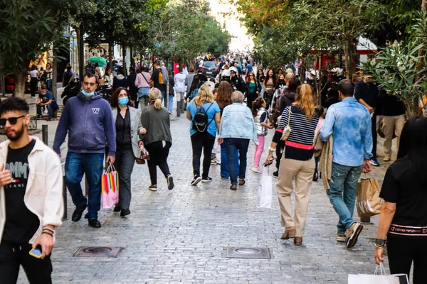 Atina, Yunanistan - Yunanistan - 07 Kasım 2021 Coronavirüs salgını sırasında Ermou Caddesi 'nde yürüyen ve alışveriş yapan kalabalık, maskeyi sokakta takmak zorunda değil, fakat pek çok kişi takıyor.