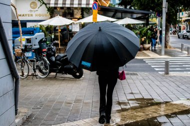 Tel Aviv, İsrail - 8 Şubat 2022 Tel Aviv sokaklarında yürüyen şemsiyeli yayalar Coronavirus salgını sırasında İsrail 'i vurdu