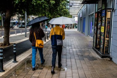 Tel Aviv, İsrail - 8 Şubat 2022 Tel Aviv sokaklarında yürüyen şemsiyeli yayalar Coronavirus salgını sırasında İsrail 'i vurdu