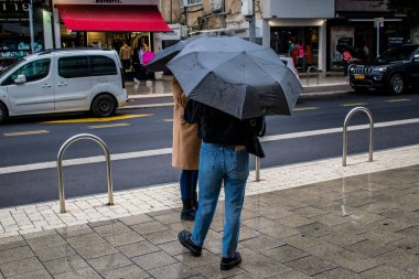 Tel Aviv, İsrail - 8 Şubat 2022 Tel Aviv sokaklarında yürüyen şemsiyeli yayalar Coronavirus salgını sırasında İsrail 'i vurdu