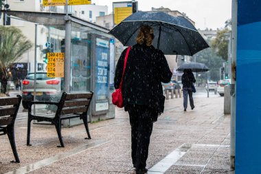 Tel Aviv, İsrail - 8 Şubat 2022 Tel Aviv sokaklarında yürüyen şemsiyeli yayalar Coronavirus salgını sırasında İsrail 'i vurdu