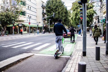 Tel Aviv, İsrail - 11 Şubat 2022 Tel Aviv sokaklarında elektrikli scooter kullanan insanlar, küçük bir iç yanmalı motorlar ve merkezde bir güverte ile çalışıyorlar.
