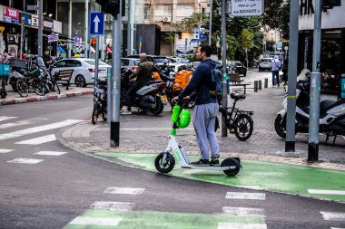 Tel Aviv, İsrail - 11 Şubat 2022 Tel Aviv sokaklarında elektrikli scooter kullanan insanlar, küçük bir iç yanmalı motorlar ve merkezde bir güverte ile çalışıyorlar.