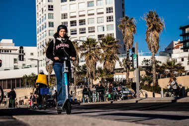 Tel Aviv, İsrail - 11 Şubat 2022 Tel Aviv sokaklarında elektrikli scooter kullanan insanlar, küçük bir iç yanmalı motorlar ve merkezde bir güverte ile çalışıyorlar.