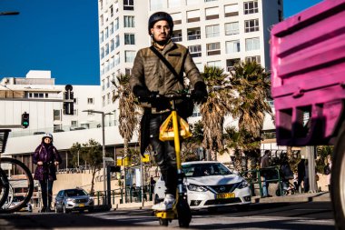 Tel Aviv, İsrail - 11 Şubat 2022 Tel Aviv sokaklarında elektrikli scooter kullanan insanlar, küçük bir iç yanmalı motorlar ve merkezde bir güverte ile çalışıyorlar.