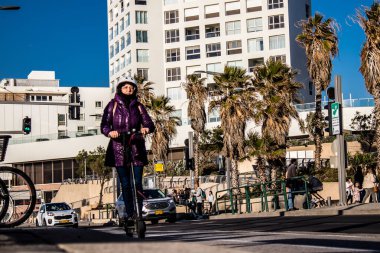 Tel Aviv, İsrail - 11 Şubat 2022 Tel Aviv sokaklarında elektrikli scooter kullanan insanlar, küçük bir iç yanmalı motorlar ve merkezde bir güverte ile çalışıyorlar.