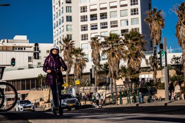 Tel Aviv, İsrail - 11 Şubat 2022 Tel Aviv sokaklarında elektrikli scooter kullanan insanlar, küçük bir iç yanmalı motorlar ve merkezde bir güverte ile çalışıyorlar.