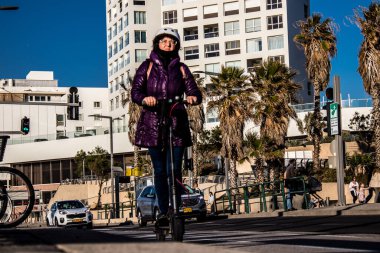 Tel Aviv, İsrail - 11 Şubat 2022 Tel Aviv sokaklarında elektrikli scooter kullanan insanlar, küçük bir iç yanmalı motorlar ve merkezde bir güverte ile çalışıyorlar.