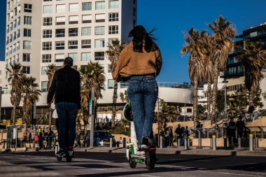 Tel Aviv, İsrail - 11 Şubat 2022 Tel Aviv sokaklarında elektrikli scooter kullanan insanlar, küçük bir iç yanmalı motorlar ve merkezde bir güverte ile çalışıyorlar.